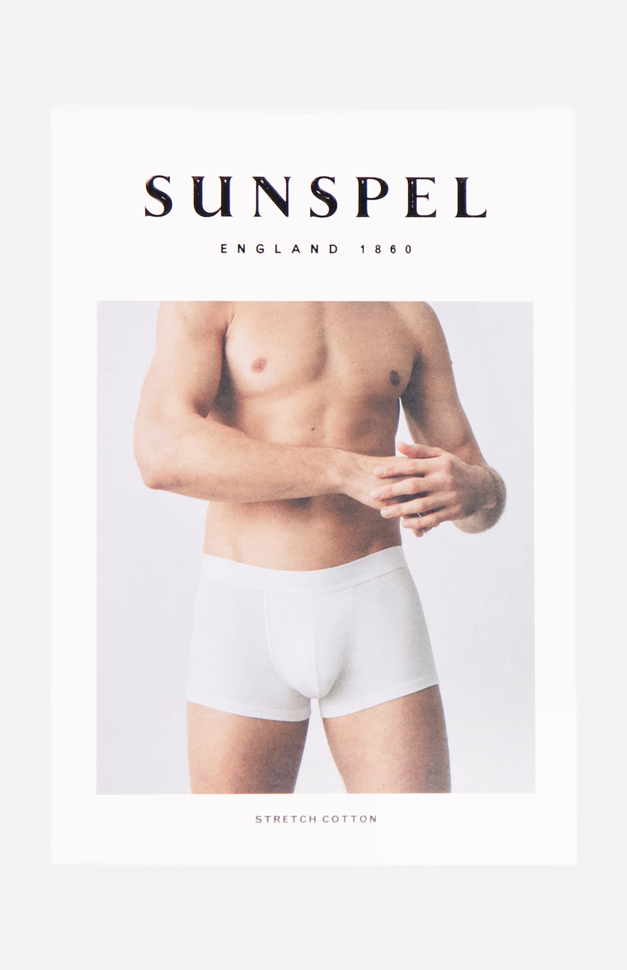 A shirtless man in white Superfine Trunk boxer briefs stands against a light background with SUNSPEL above and STRETCH COTTON below, highlighting men's underwear crafted from superfine cotton jersey on the packaging.