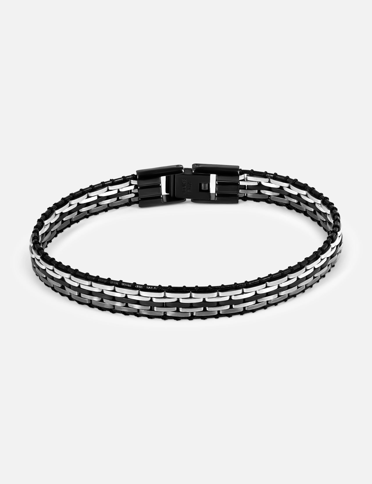 The TATEOSSIAN Tessellate Steel and Leather Bracelet, featuring a modern industrial design and a black rectangular clasp, is displayed in a circular shape against a plain white background.