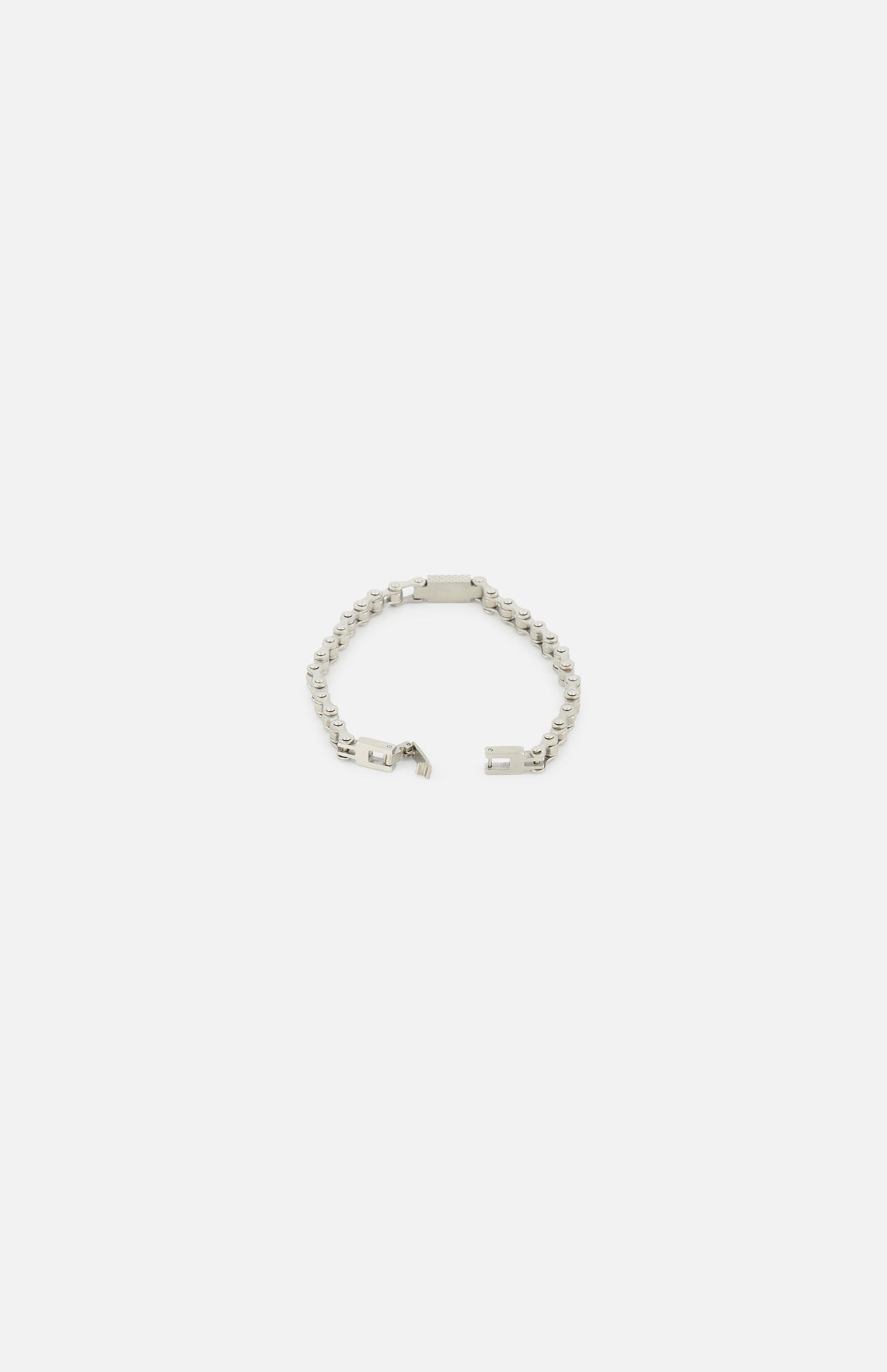 The TATEOSSIAN Bici Chain Bracelet is a luxury silver stainless steel accessory featuring a central rectangular plate. Shown partially unfastened on a white background, it highlights its polished links and clasp.