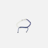 The TATEOSSIAN Feng Shui Fish Macrame Bracelet features half white and half navy blue beading, blue sodalite beads, and a navy blue sliding knot closure with two loose cord ends, shown on a plain white background.