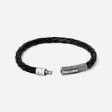 The TATEOSSIAN Vintage Herringbone Click Bracelet features black braided leather and a textured stainless steel clasp, displayed open against a plain light gray background—a sophisticated men's luxury accessory.