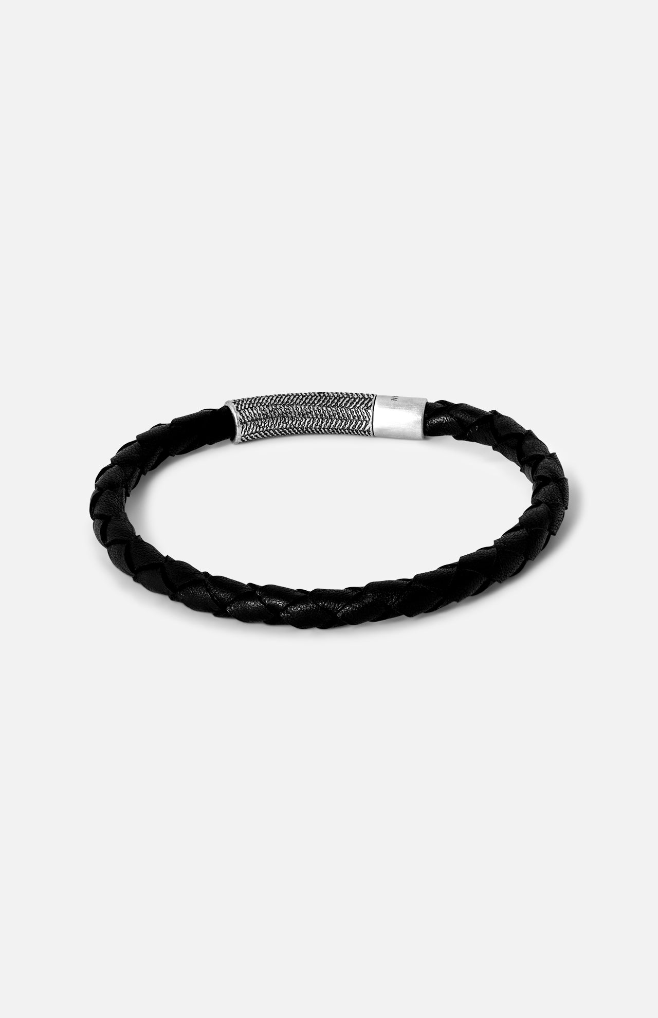 The Vintage Herringbone Click Bracelet by TATEOSSIAN features black braided leather and a stainless steel clasp, shown on a plain light gray background—a refined men's luxury accessory.