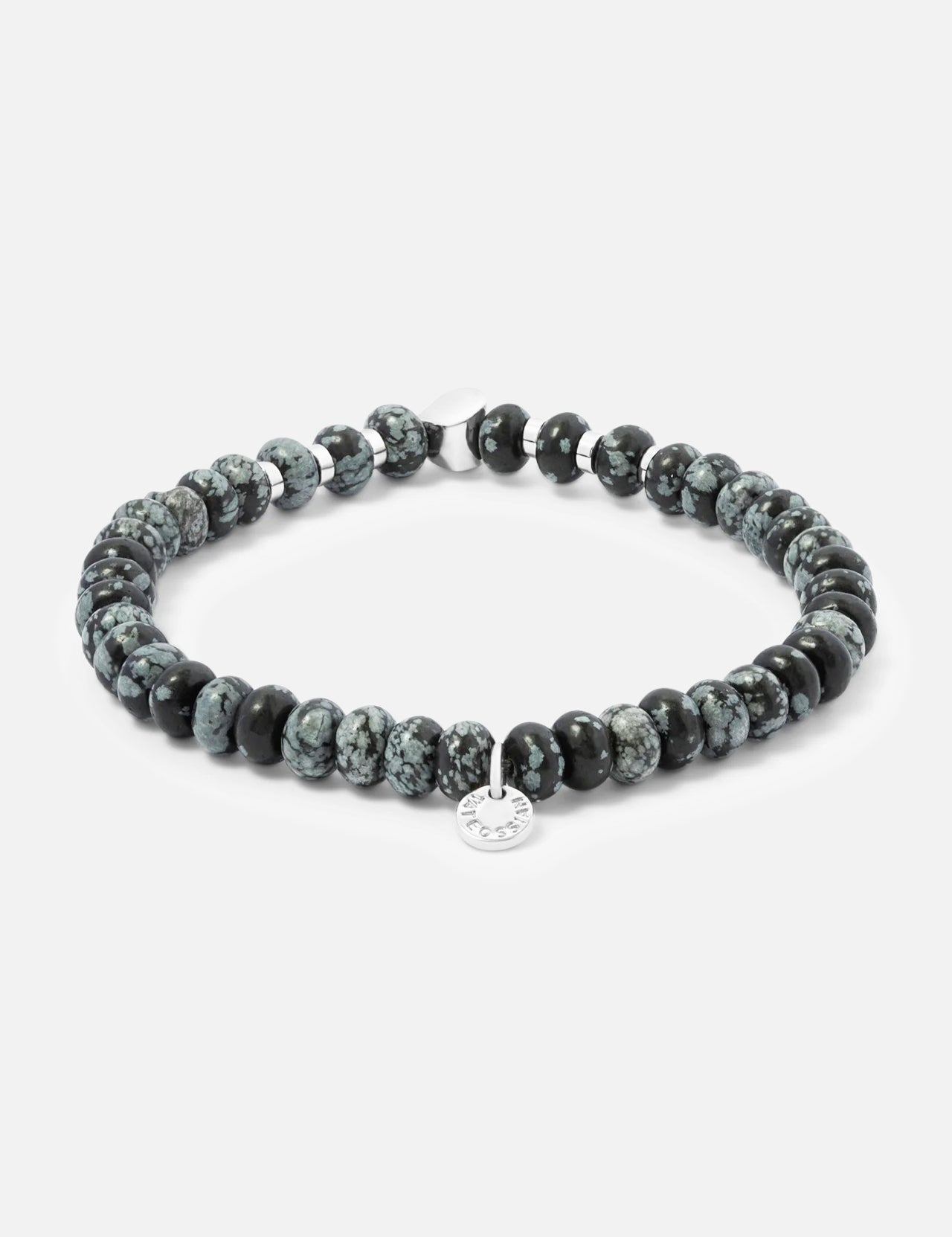 The Snowflake Obsidian Bracelet by TATEOSSIAN features round, marbled black and gray stones and a small, engraved sterling silver charm.