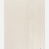 Cream-colored rectangular TEKLA Lambswool Blanket with a small woven brand tag in the bottom right corner.
