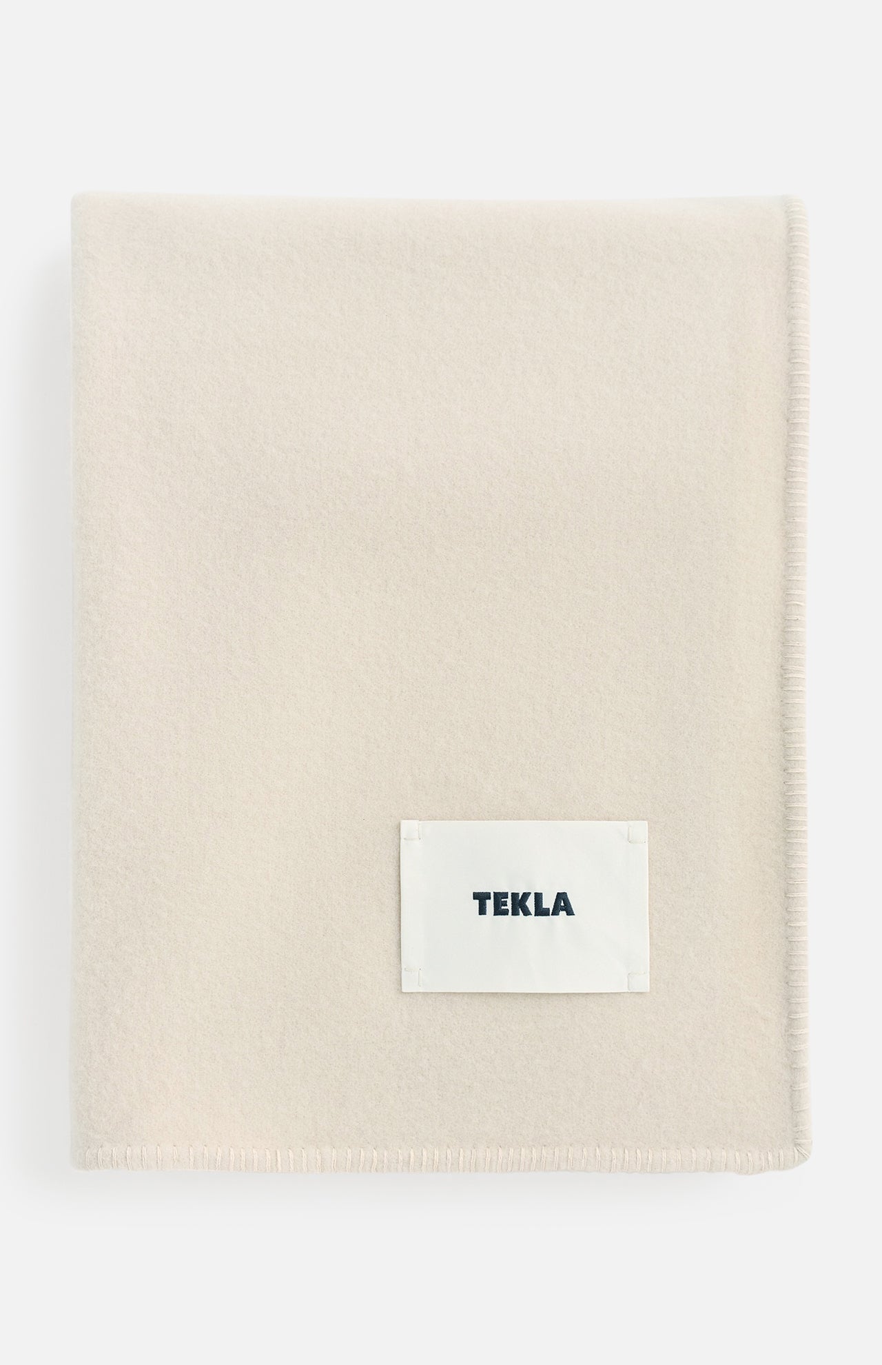 Off-white TEKLA Lambswool Blanket with a stitched label in the corner.