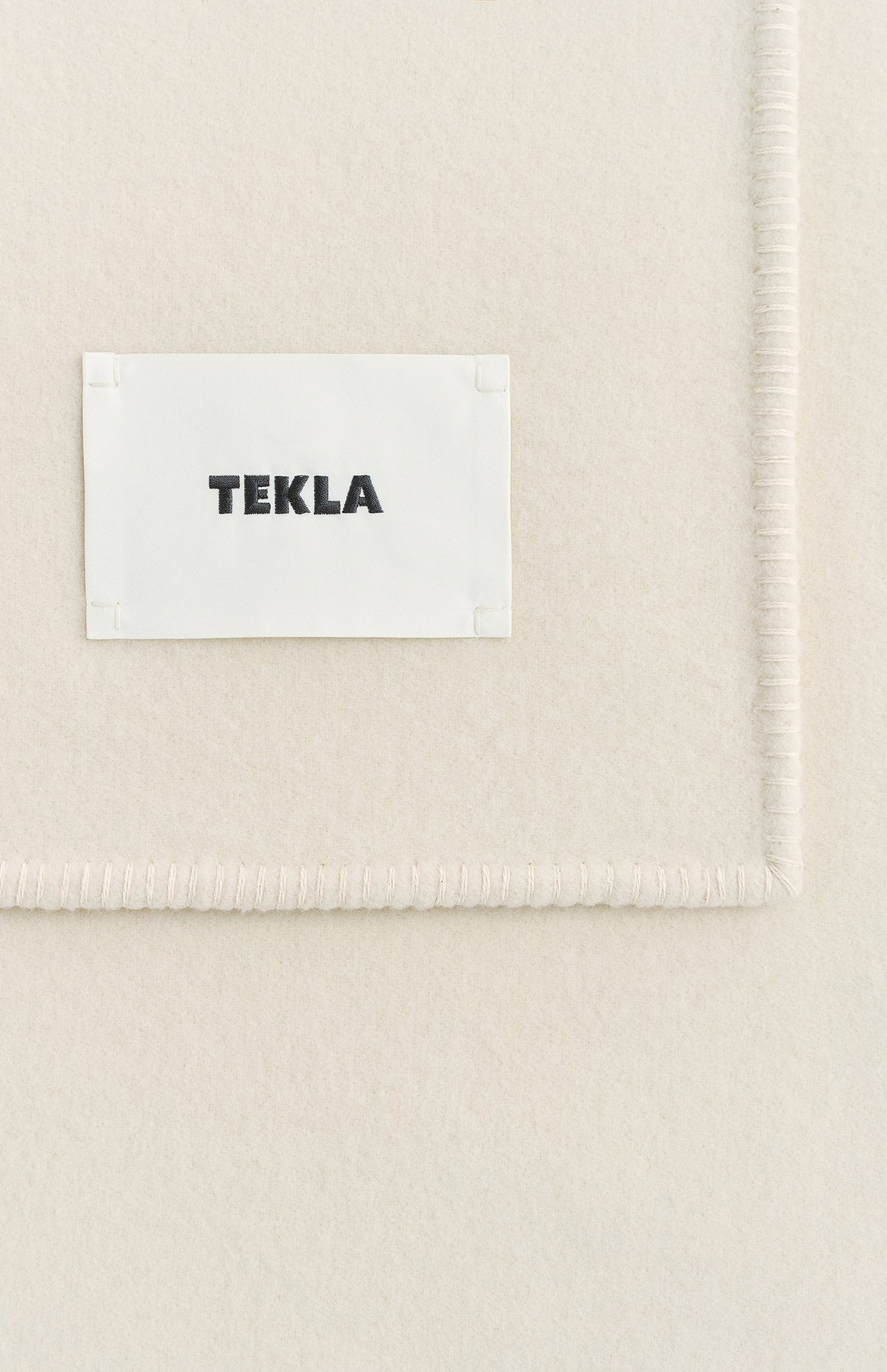 Off-white Lambswool Blanket with a stitched edge and a white TEKLA label in black text.