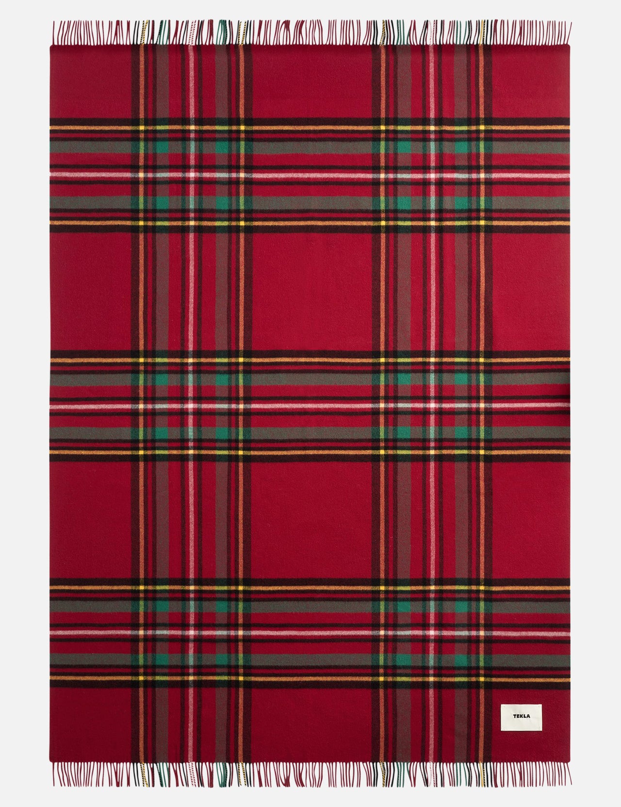 TEKLA Lambswool Fringed Blanket in red plaid with green, yellow, and black stripes and a fringed edge.