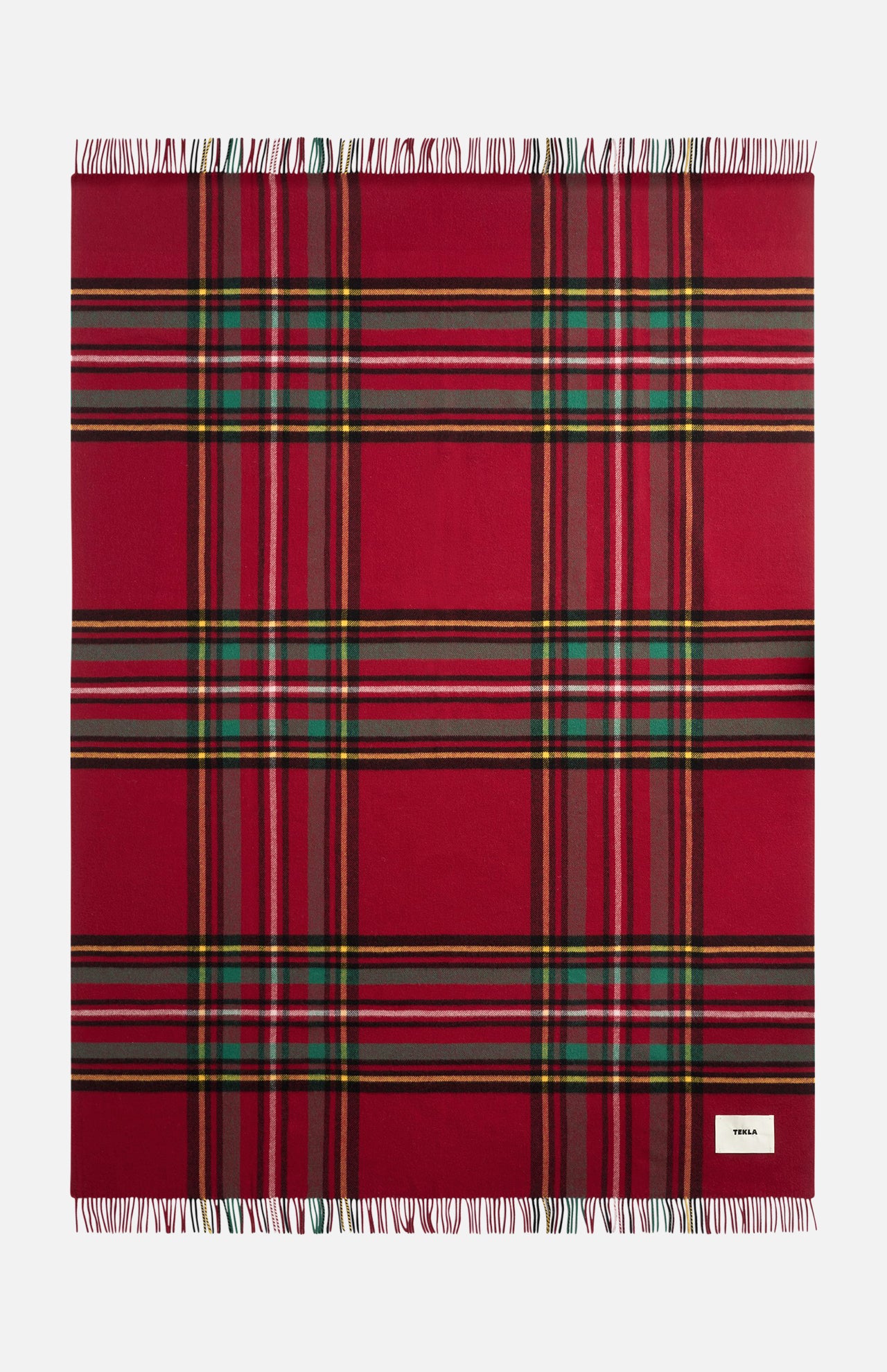 TEKLA Lambswool Fringed Blanket in red plaid with green, yellow, and black stripes and a fringed edge.