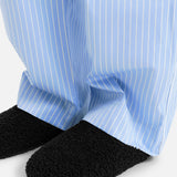 Black TEKLA Shearling Slippers with a cushioned footbed worn with light blue and white striped pajama pants.