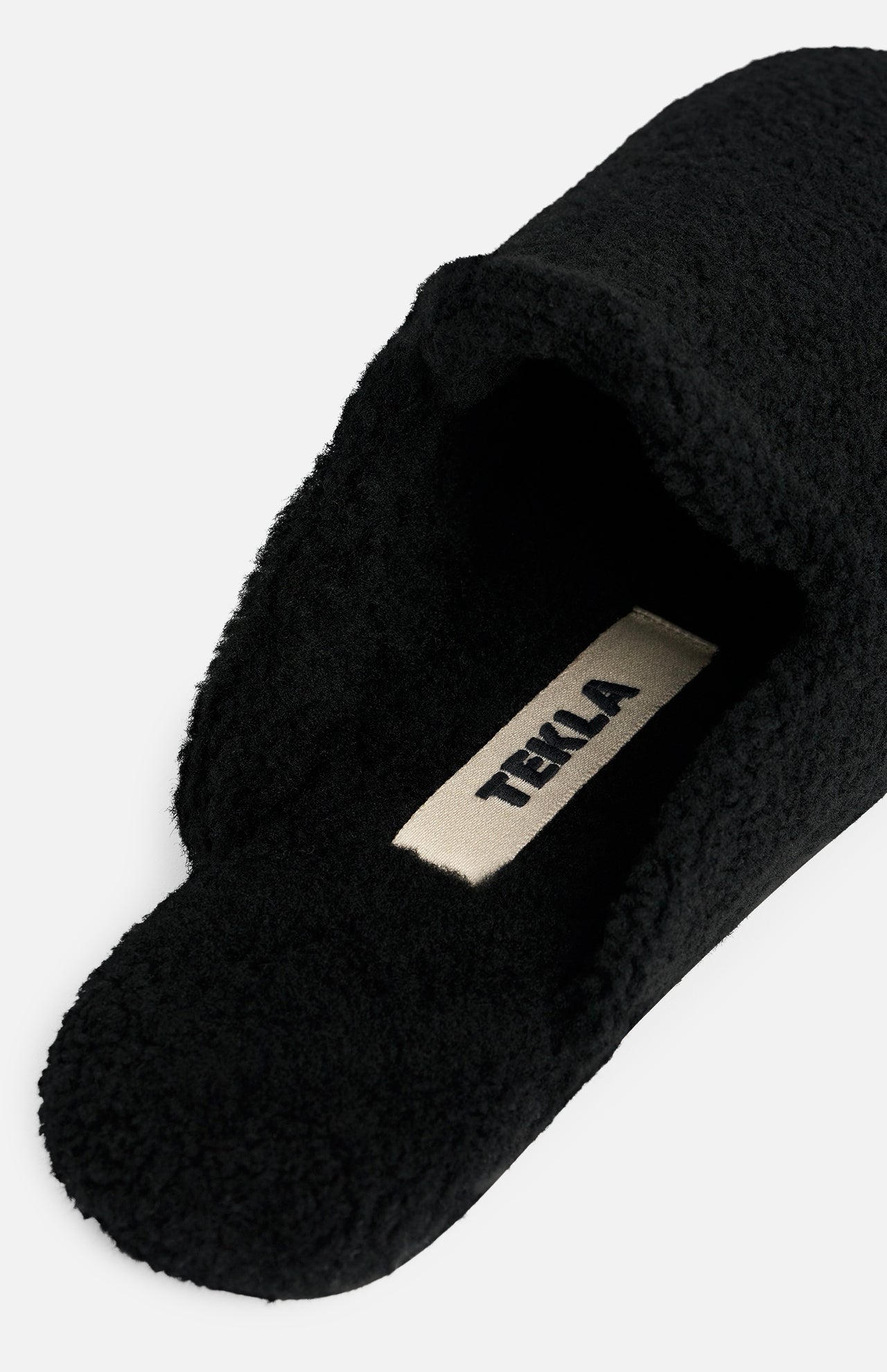 Black TEKLA Shearling Slippers with a cushioned footbed and a branded interior label.