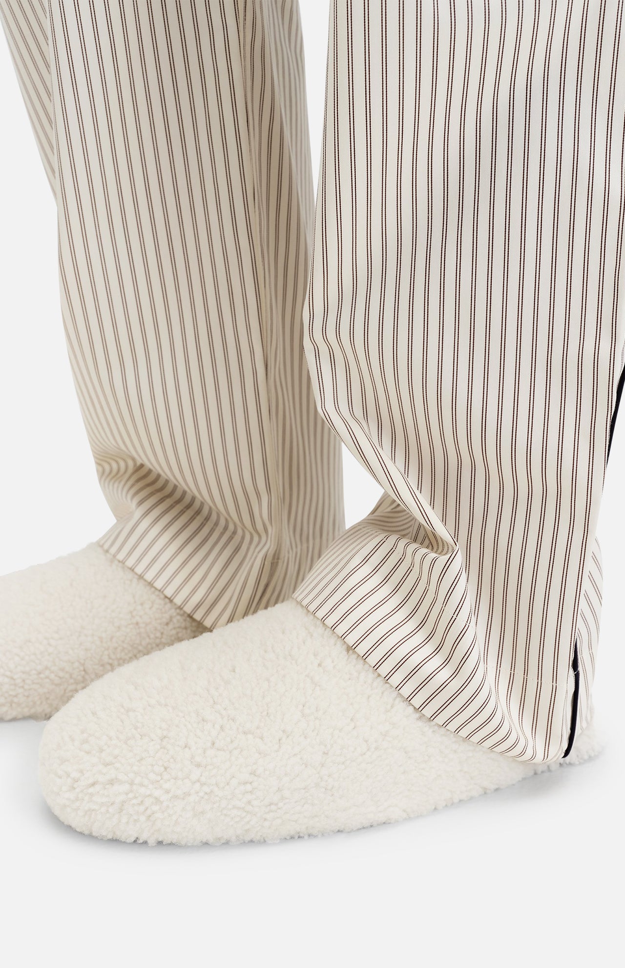 Off-white TEKLA Shearling Slippers with a cushioned footbed worn with striped pajama pants.