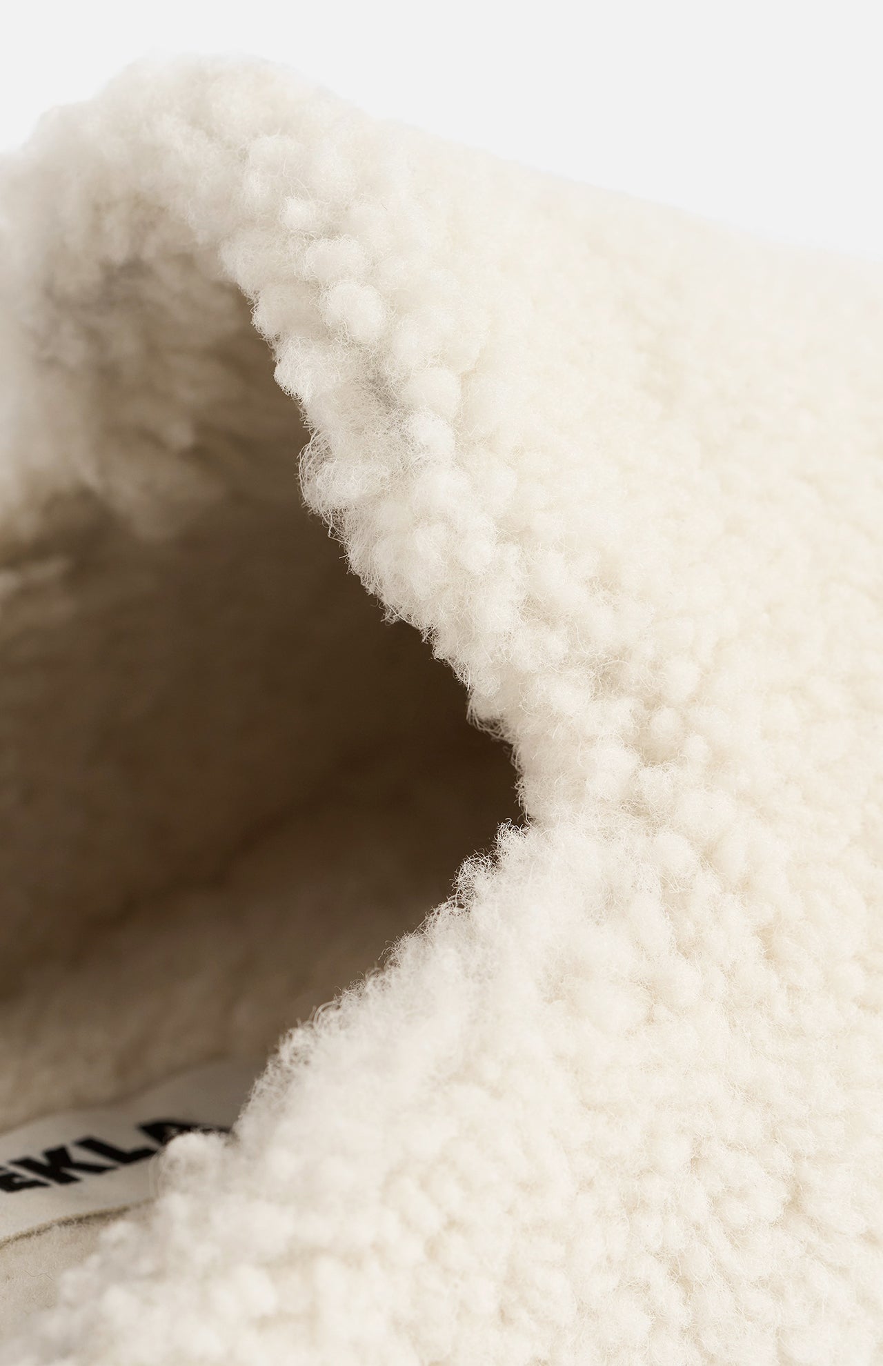 Close-up of the opening of a cream-colored TEKLA Shearling Slipper with a cushioned footbed.