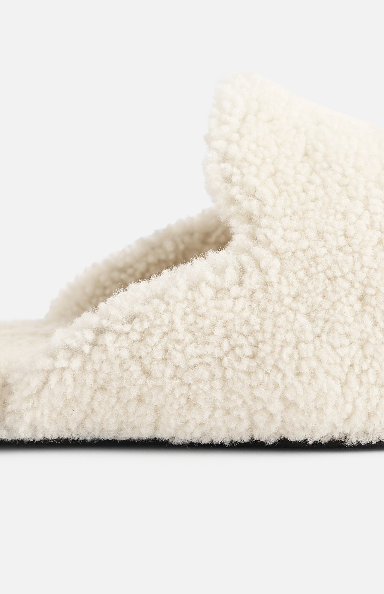 Close-up of a cream-colored TEKLA Shearling Slipper with a cushioned footbed and a dark sole.