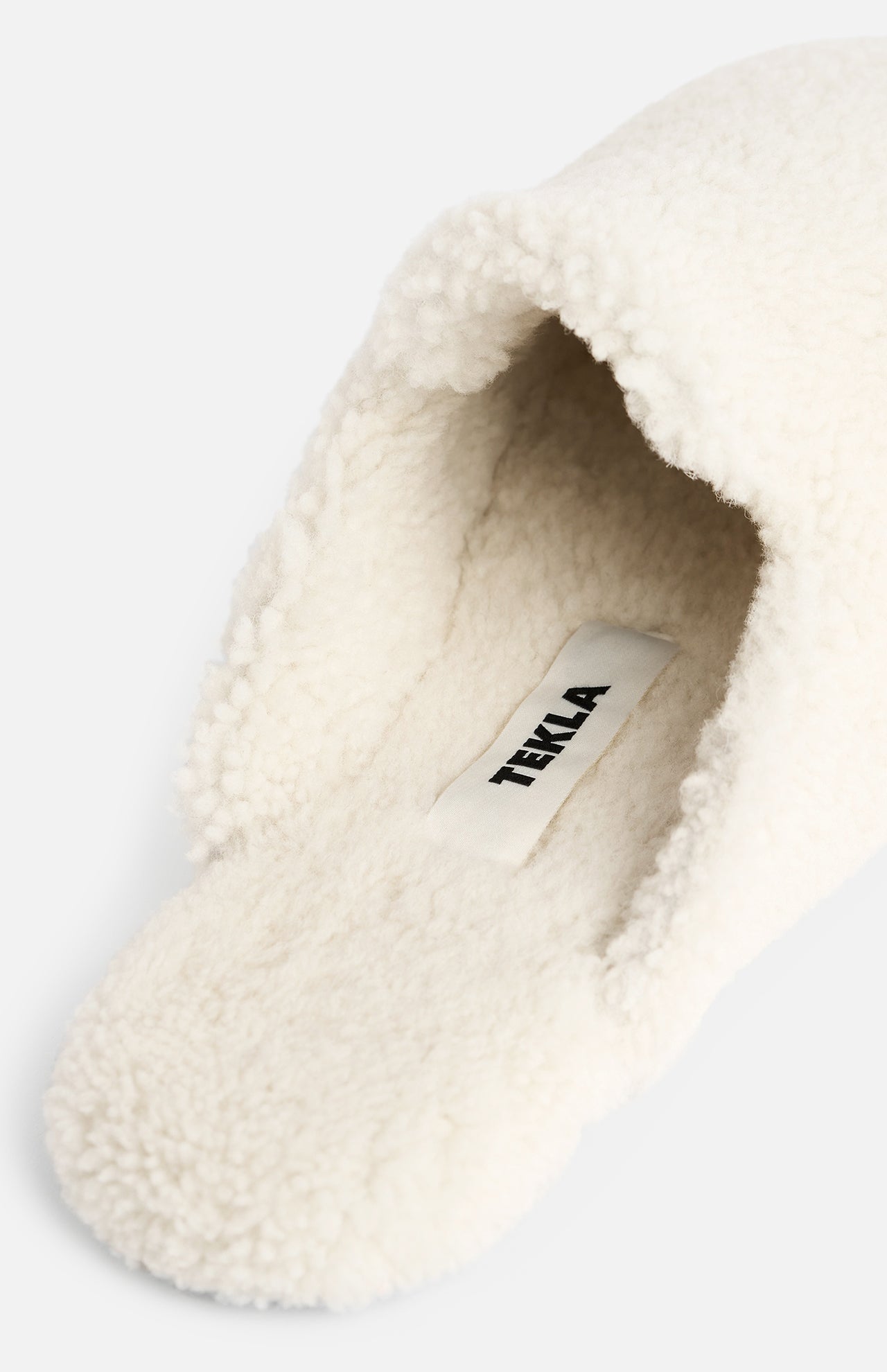 Off-white shearling TEKLA Shearling Slippers featuring a branded fabric label on the cushioned footbed.