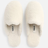 A pair of cream-colored TEKLA Shearling Slippers with a cushioned footbed, viewed from above.
