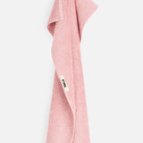 A pink organic cotton TEKLA Terry Bath Towel hanging from a loop.