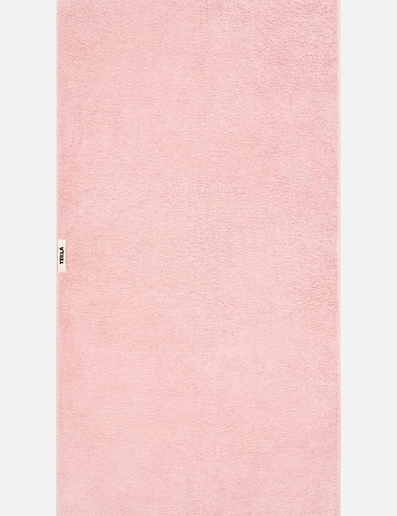 A light pink TEKLA Terry Bath Towel in organic cotton with a small branded label on the left edge.