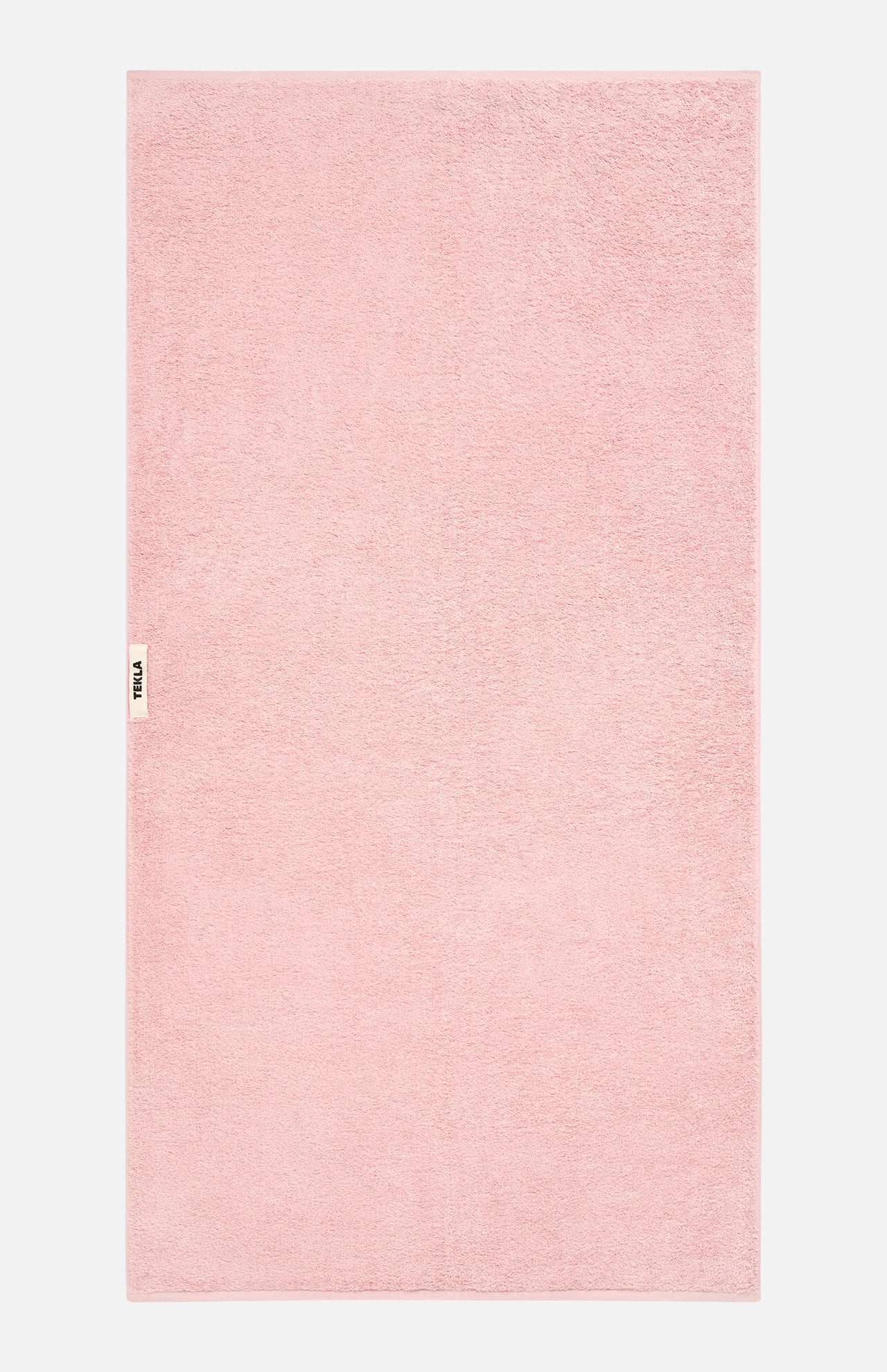 A light pink TEKLA Terry Bath Towel in organic cotton with a small branded label on the left edge.