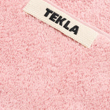 Pink organic cotton terry cloth Terry Bath Towel with a white TEKLA label featuring the brand name in black text.