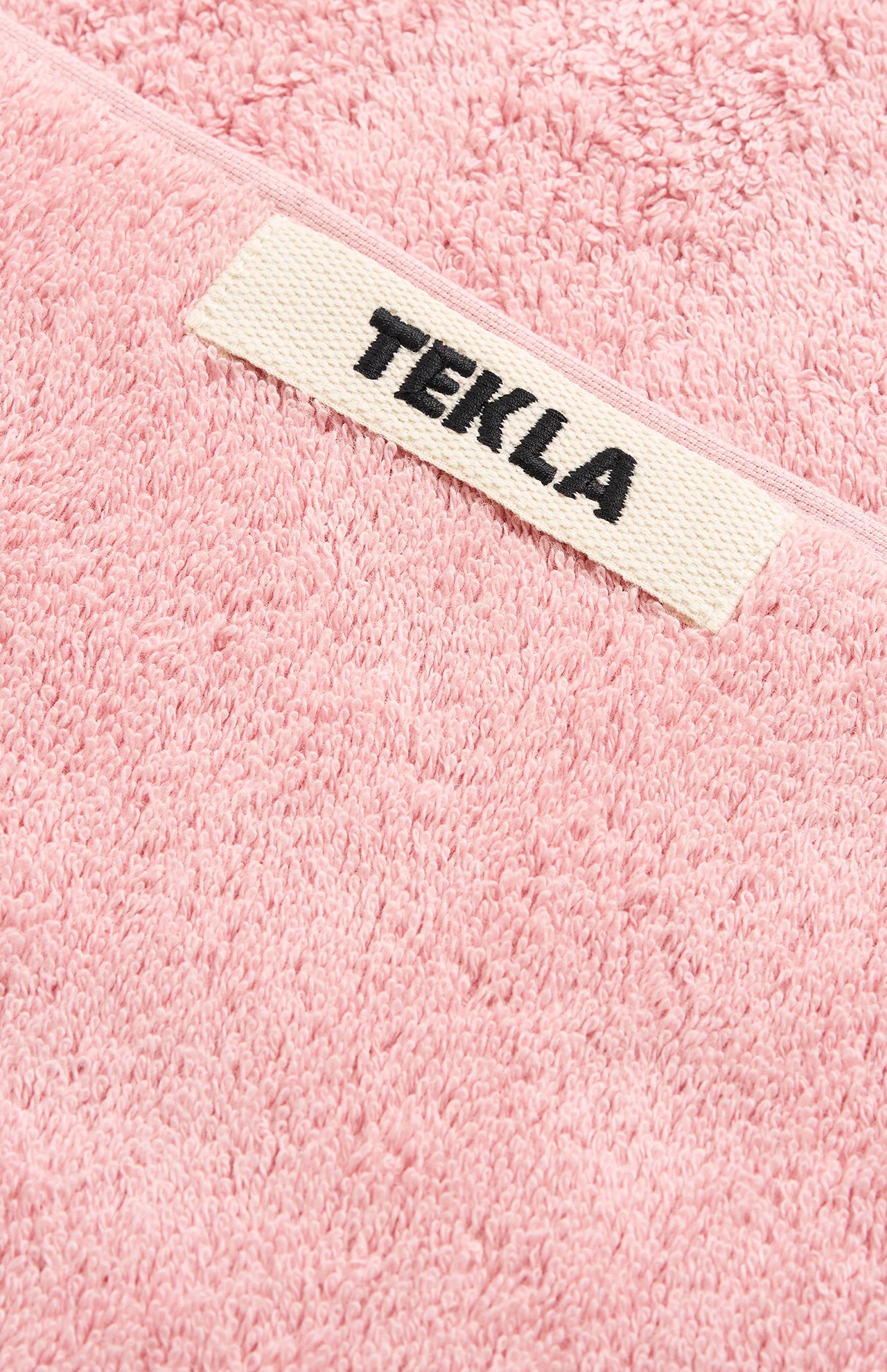 Pink organic cotton terry cloth Terry Bath Towel with a white TEKLA label featuring the brand name in black text.