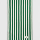 Rectangular dark green TEKLA Terry Beach Towel with alternating dark green and white vertical stripes and a small rectangular logo patch in the corner.