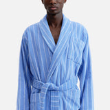 A person wearing a blue and white striped organic cotton Terry Classic Unisex Bathrobe with a tie waist.