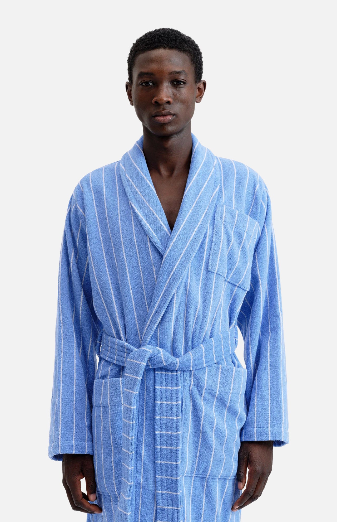 A person wearing a blue and white striped organic cotton Terry Classic Unisex Bathrobe with a tie waist.