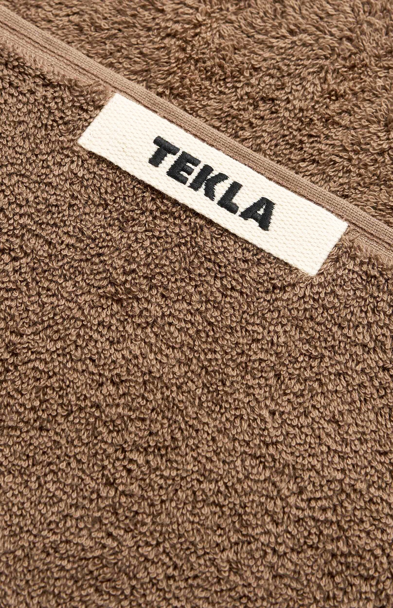 Brown organic cotton Terry Towel Washcloth with a white fabric tag labeled TEKLA in black text.