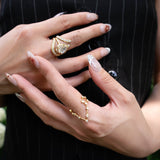 Close-up of a person’s hands with long, decorated nails adorned with multiple gold rings—including the LOGAN HOLLOWELL Pisces Diamond Constellation Ring—set against their black pinstriped vest. The image highlights the jewelry and manicure, drawing attention to the elegant zodiac-inspired design of the diamond constellation ring.