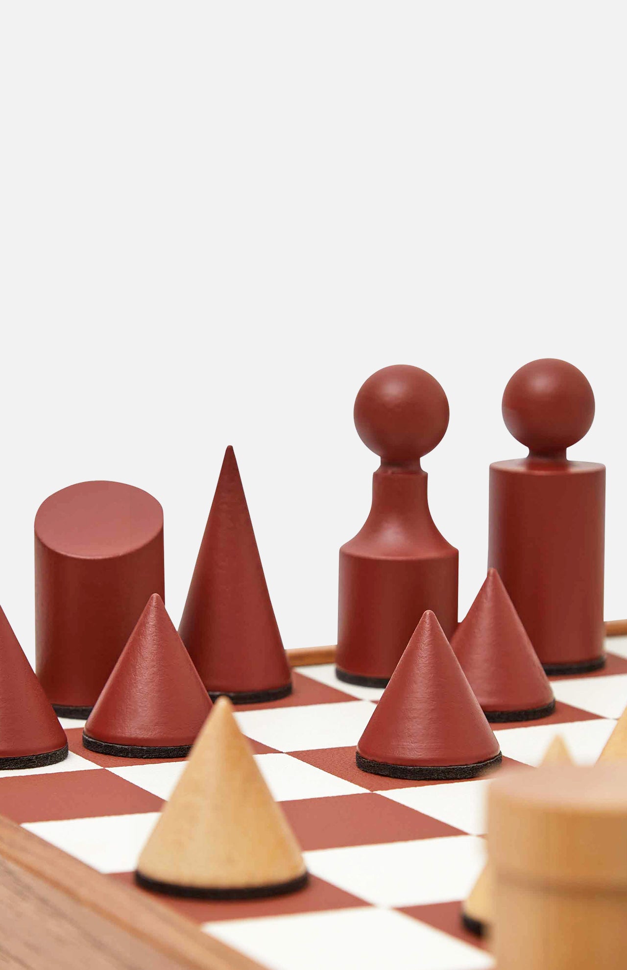 The Milos Terracotta Chess Game Set by THE CONRAN SHOP features a modern minimalist design with geometric brown and tan pieces—cones, cylinders, and spheres—on a handcrafted wooden board for an abstract, elegant look.