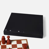 The Milos Terracotta Chess Game Set by THE CONRAN SHOP features abstract brown and tan pieces on a wooden board with a matching black box labeled T C S, all shown on a white background.