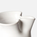 Close-up of the Puglia Jug with Plaited Handle by THE CONRAN SHOP, featuring a smooth white stoneware finish and elegantly curved spout, highlighting refined Italian craftsmanship against a plain light background.