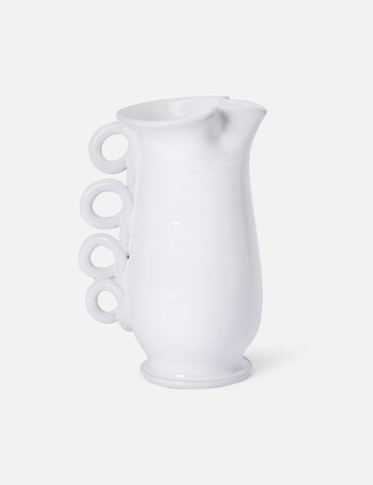 The Puglia Jug with Ring Handle by THE CONRAN SHOP is a white ceramic pitcher inspired by Puglia ceramics, featuring a curved body and four ring handles stacked vertically on one side.
