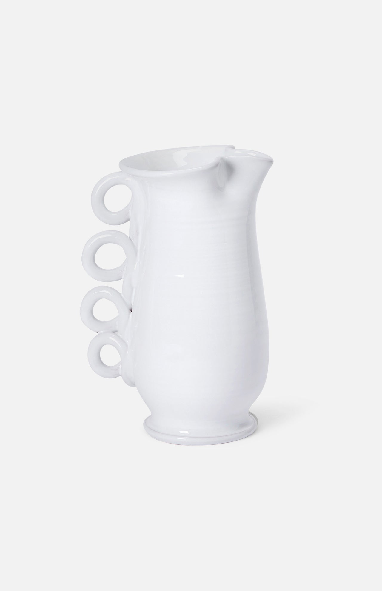 The Puglia Jug with Ring Handle by THE CONRAN SHOP is a white ceramic pitcher inspired by Puglia ceramics, featuring a curved body and four ring handles stacked vertically on one side.