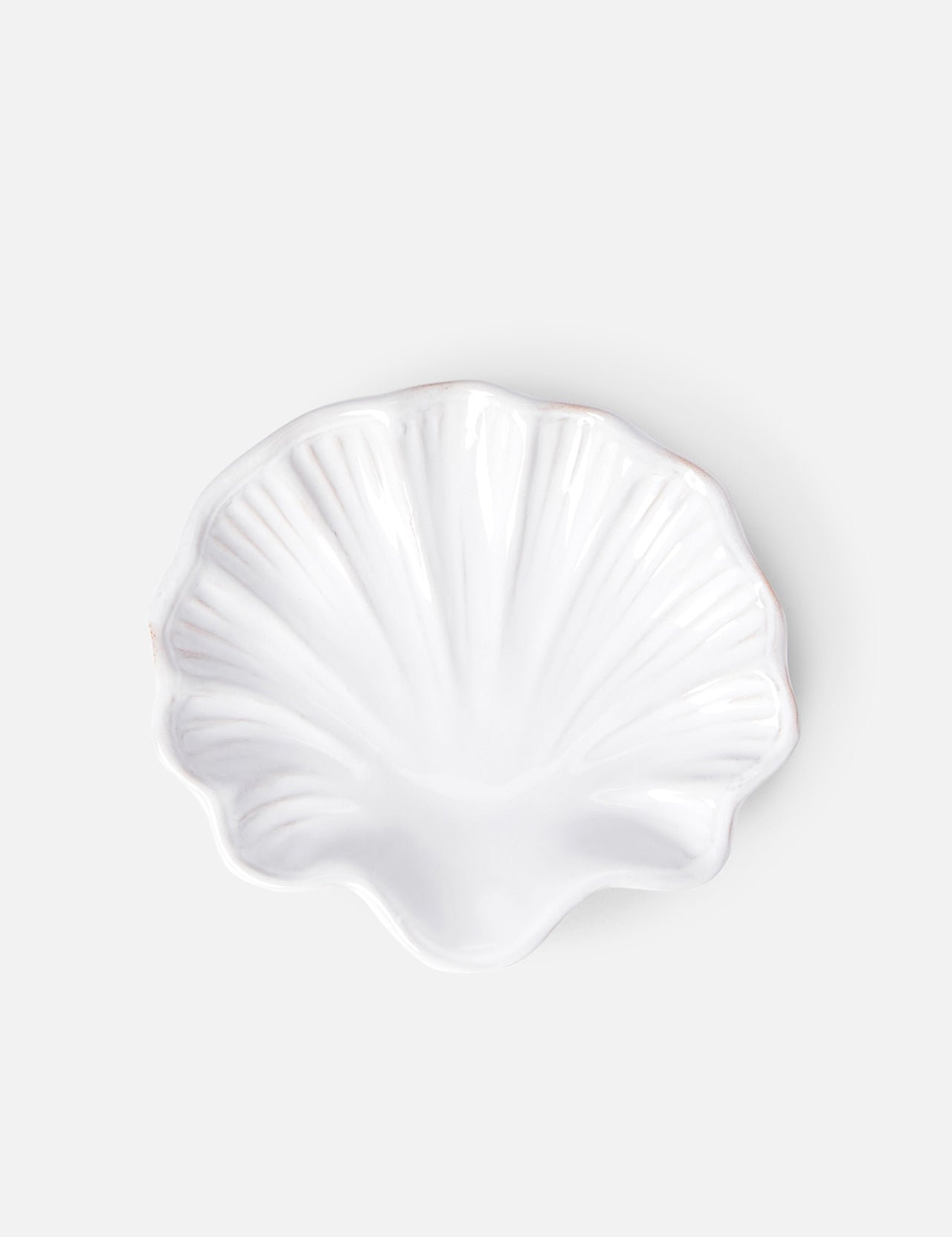 The Puglia Stoneware Shell Dish by THE CONRAN SHOP, shaped like a seashell, brings elegant coastal charm to any space with its handcrafted Italian ceramic design and light gray background.