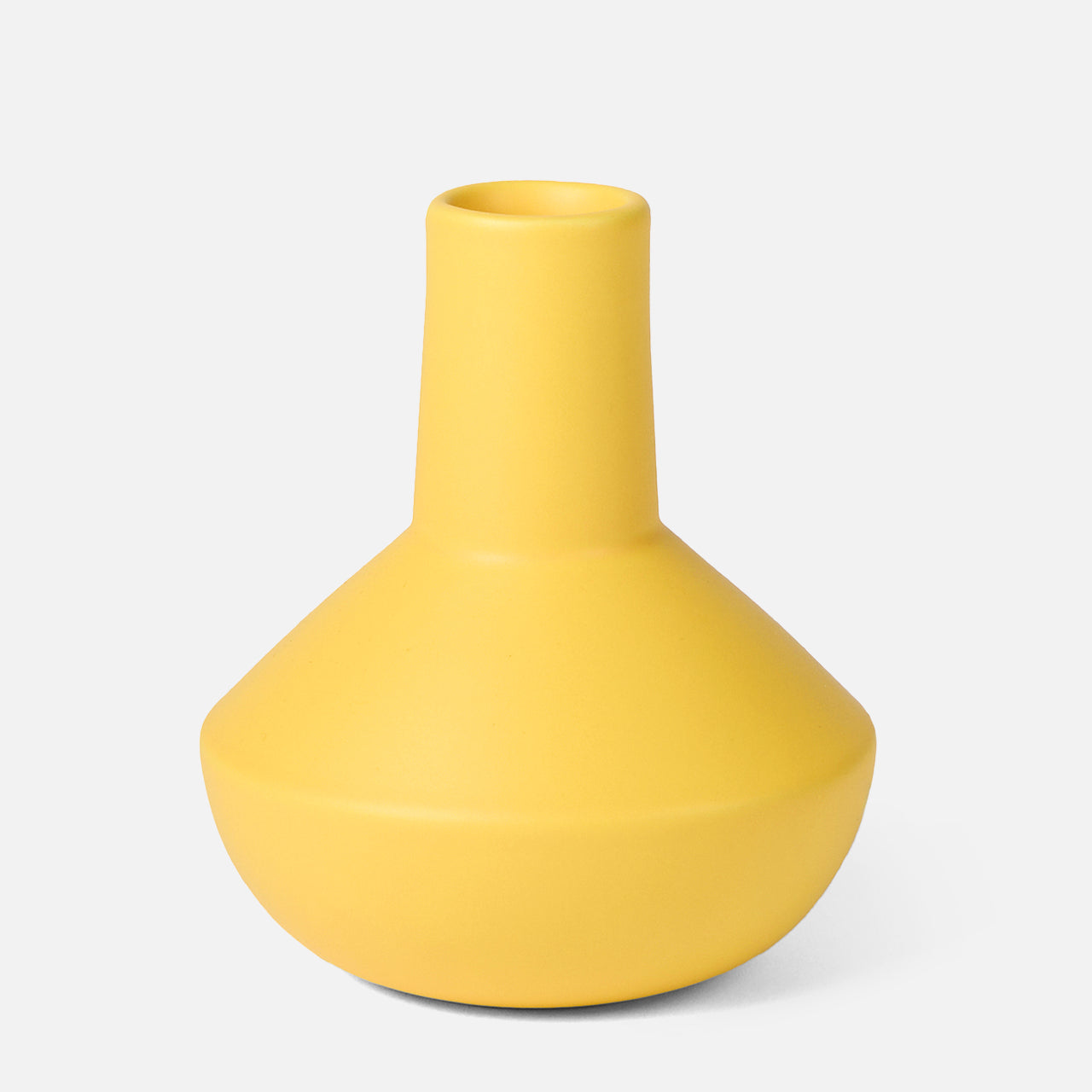 The Sphere Bottle Vase by THE CONRAN SHOP is a modern, matte yellow earthenware piece with a wide, flat base and a narrow cylindrical neck, shown here against a plain white background.
