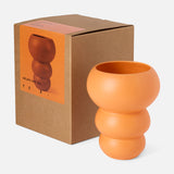 The CONRAN SHOP's Stacked Spheres Vase Orange, crafted in sculptural earthenware with three rounded segments, is shown beside its brown box featuring a product image and description on the front.