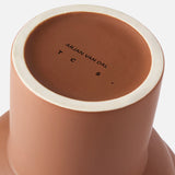 Close-up of the base of the Tree Vase Cocao by THE CONRAN SHOP, matte brown finish, with branding printed in black and viewed from below against a white background.