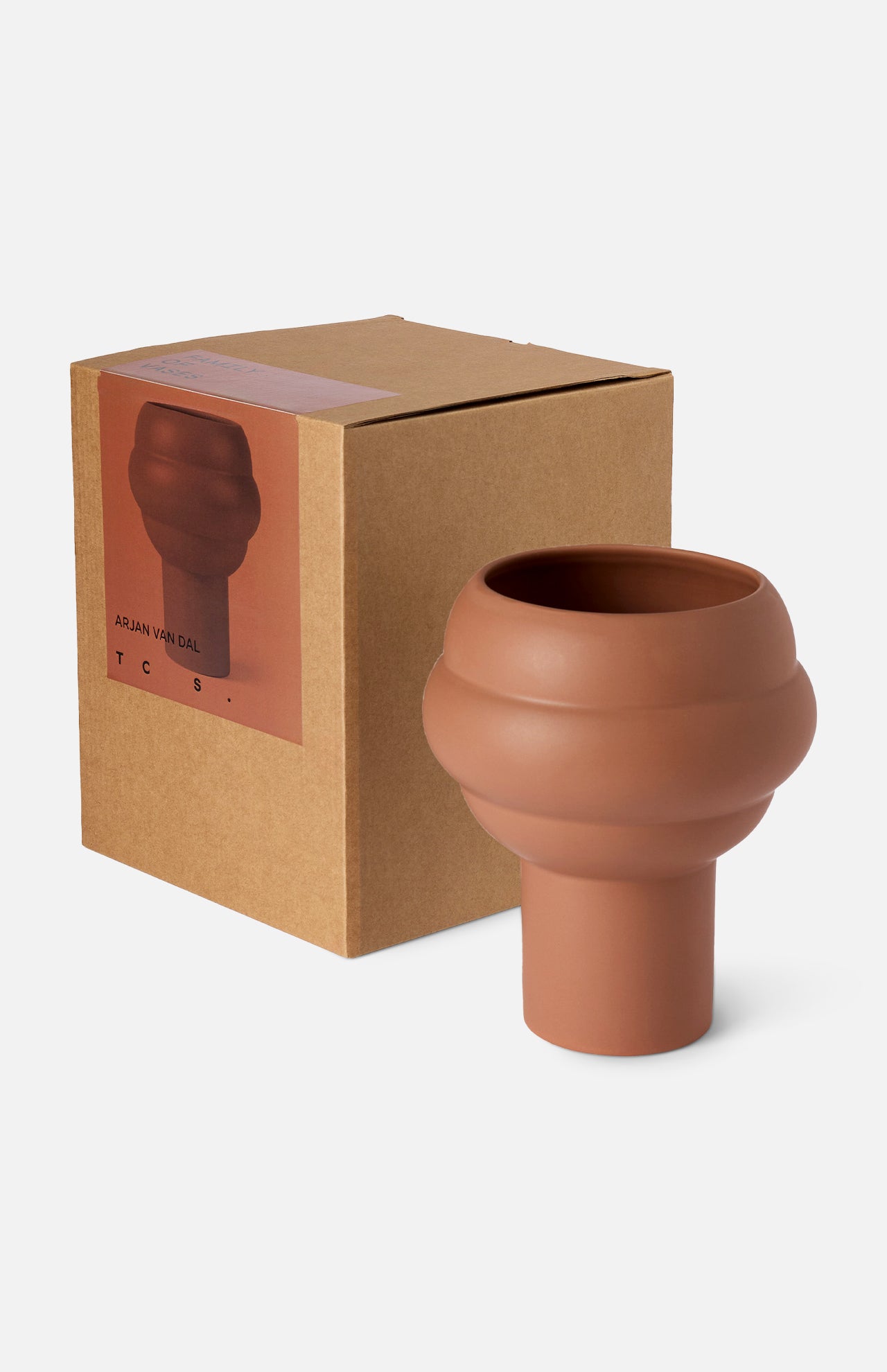 The Tree Vase Cocao by THE CONRAN SHOP, a matte terracotta-hued earthenware piece with a sculptural, rounded form, is displayed beside its brown box featuring the vase’s image and product details on the label.