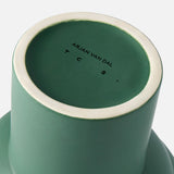 A close-up of the base of the Tree Vase Forest Green from THE CONRAN SHOP, featuring a white rim and Arjan Van Dal’s name with the initials T C S . printed in black on the bottom.