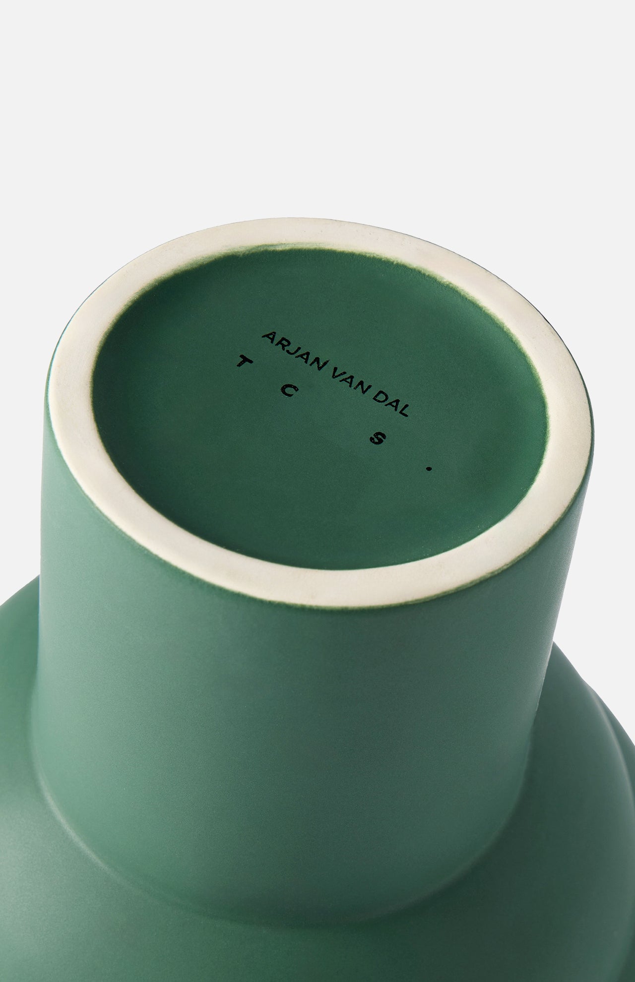 A close-up of the base of the Tree Vase Forest Green from THE CONRAN SHOP, featuring a white rim and Arjan Van Dal’s name with the initials T C S . printed in black on the bottom.