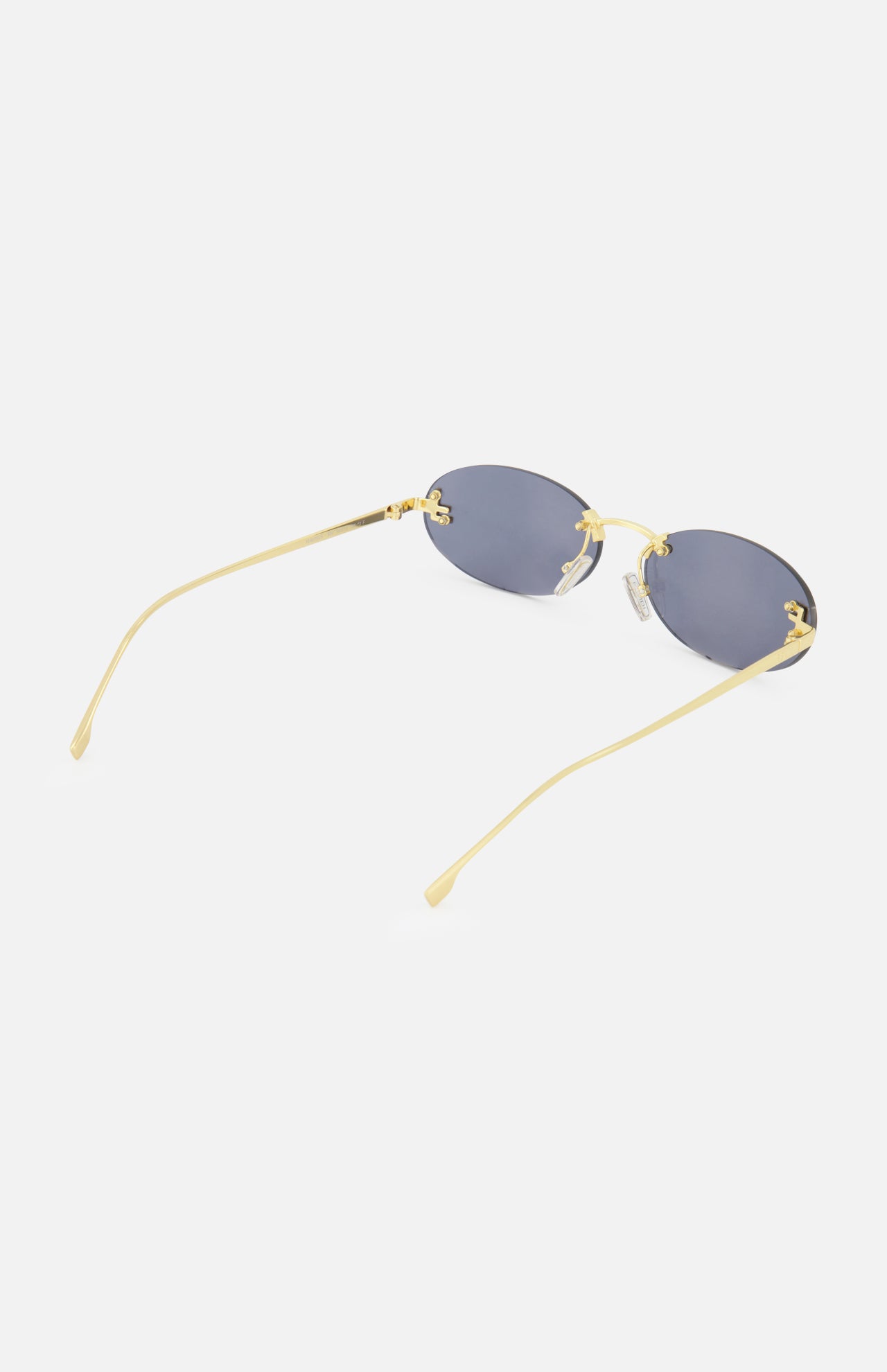 The Fendi Oval Gold Sunglasses by FENDI feature gold-rimmed oval frames with dark lenses and subtle gold FENDI lettering along the arms. Shown on a white background with the arms extended, these statement sunglasses are perfect for any occasion.