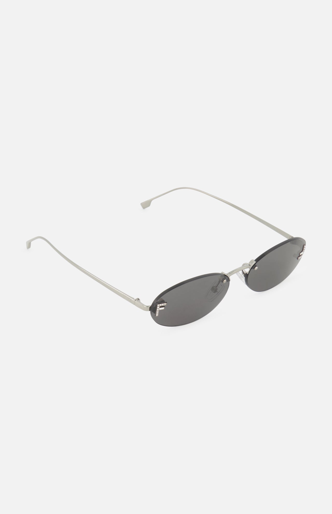 Introducing the Fendi Oval Silver Sunglasses by FENDI, featuring an oval-shaped, rimless design with thin silver metal frames and dark lenses. Displayed on a white background, these sunglasses showcase minimalist elegance with curved arms, making them a sophisticated accessory for any occasion.