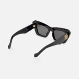 LOEWE Cat Eye Black Sunglasses feature dark lenses, a gold emblem on the temple, and an engraved brand name on the inner arm, displayed against a plain light background.