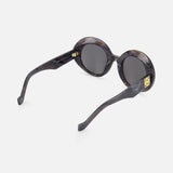 LOEWE Round Grey-black Sunglasses feature marble-inspired dark grey frames, black lenses, curved arms, and a gold logo at the temple near the hinges for a stylish look.