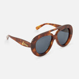 The Loewe Aviator Brown Tortoiseshell Sunglasses by LOEWE feature modern oval frames with dark lenses and a gold LOEWE logo on the left temple, elegantly showcased against a white background.