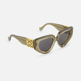 Loewe Cat Eye Taupe Sunglasses by LOEWE feature thick acetate cat-eye frames, taupe color, smoke lenses, and gold accents on the temples, shown against a plain white background.