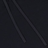 Close-up of the THEORY Delory Drawstring Hoodie Sweater in black, showing two flat black drawstrings lying diagonally across the textured knit fabric.