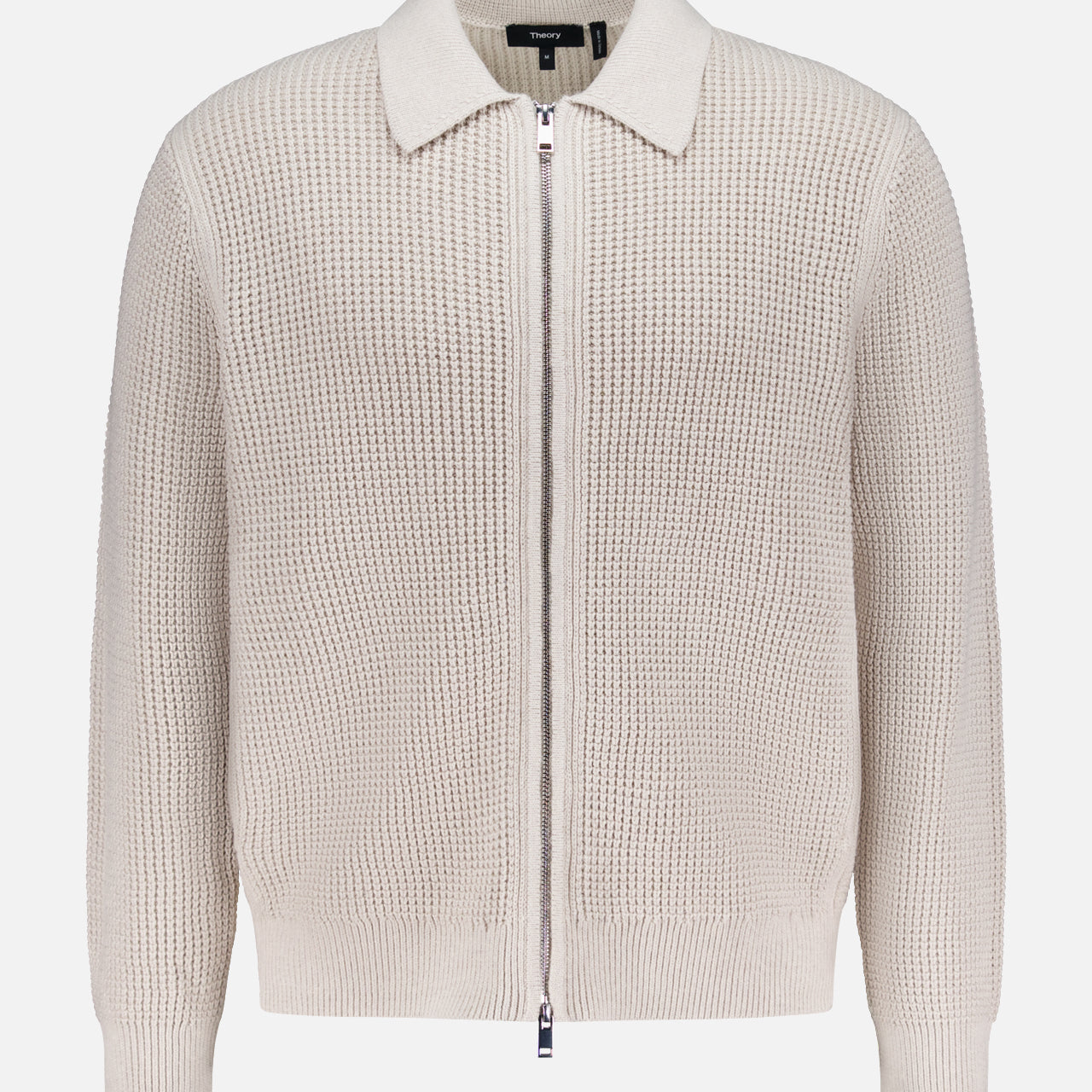 The THEORY Gary Zip Sweater Jacket features a beige waffle-knit texture, long sleeves, front zipper closure, and classic collar, shown against a plain white background.