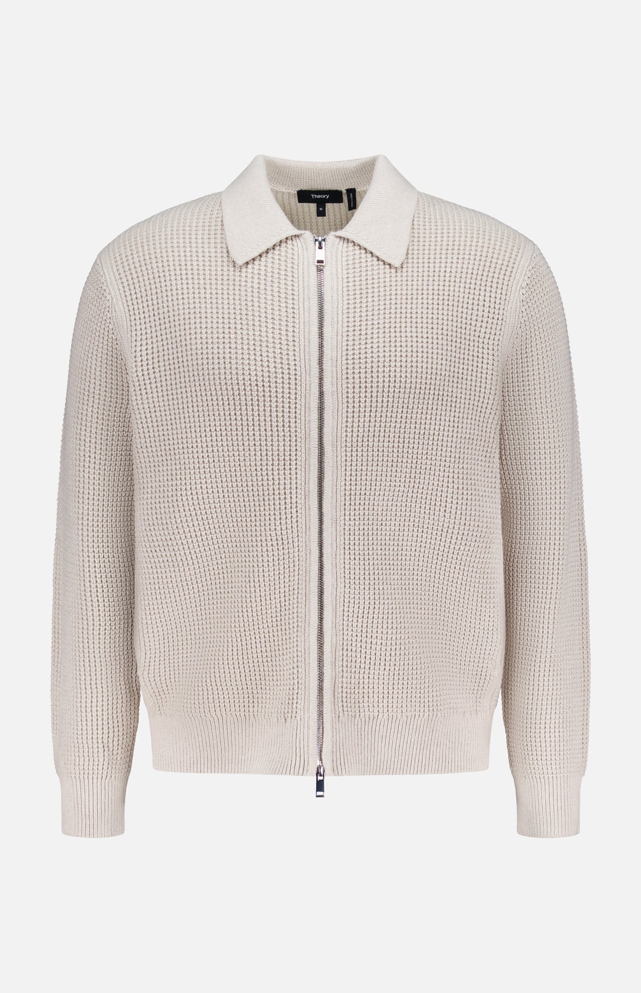 The THEORY Gary Zip Sweater Jacket features a beige waffle-knit texture, long sleeves, front zipper closure, and classic collar, shown against a plain white background.